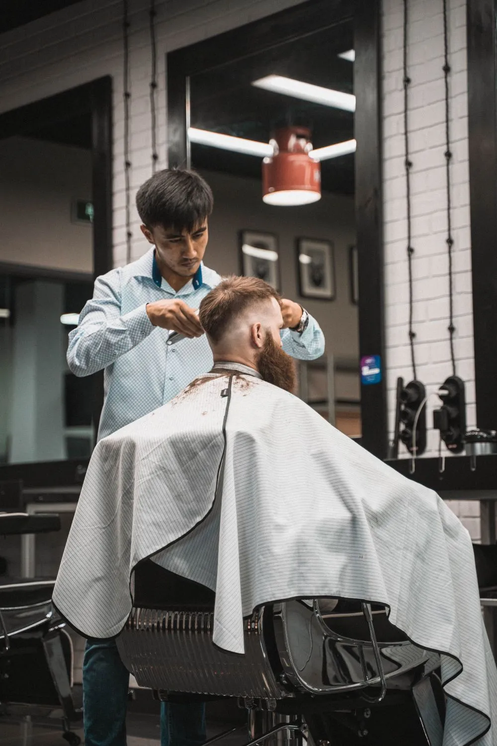Um barbeiro a cortar o cabelo de um cliente